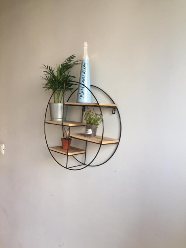 Prateleira circular fixada na parede, com três níveis, cada um com um vaso de planta.