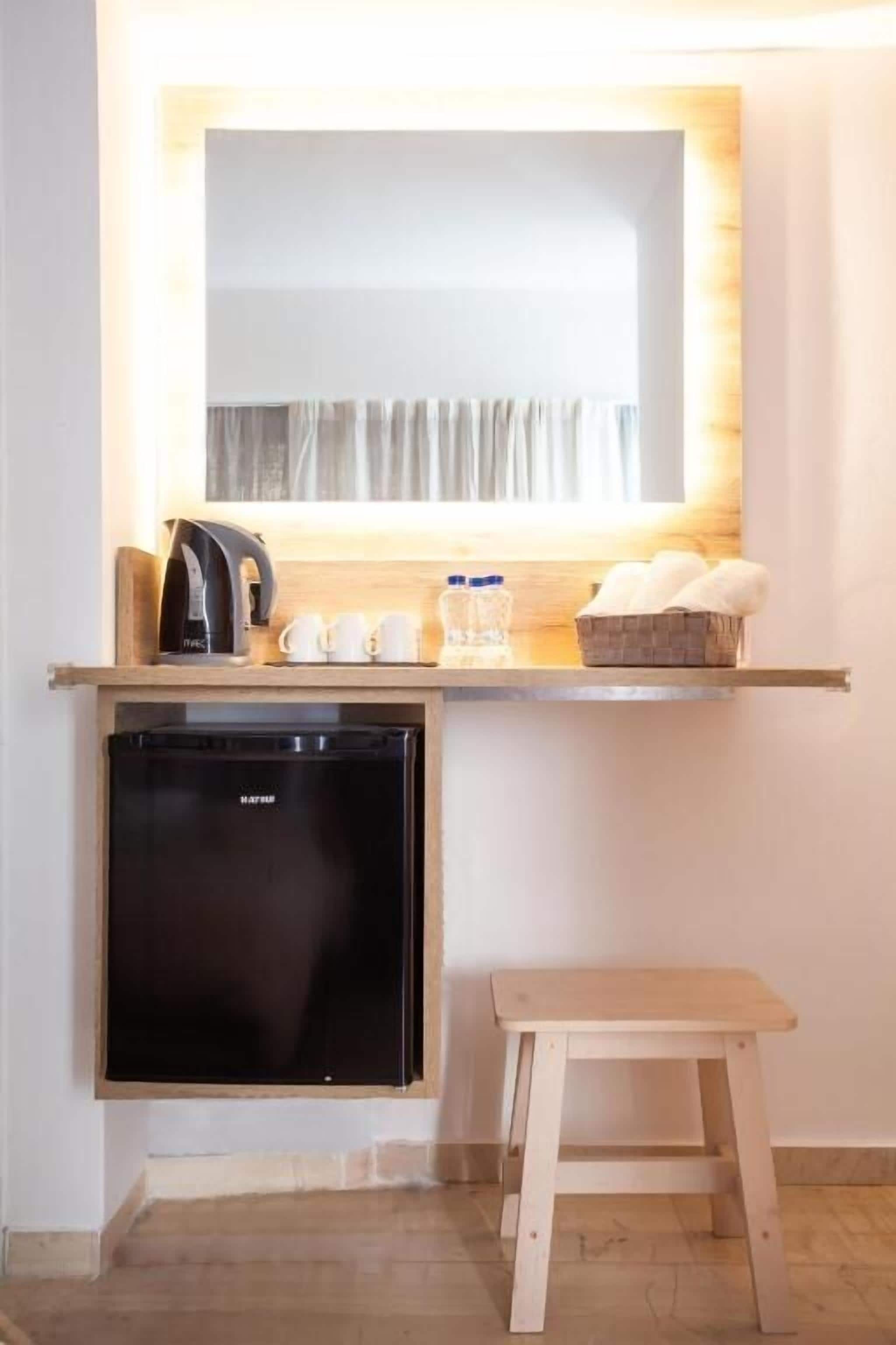 A compact kitchenette with a built-in refrigerator, a coffee maker, and a small table.
