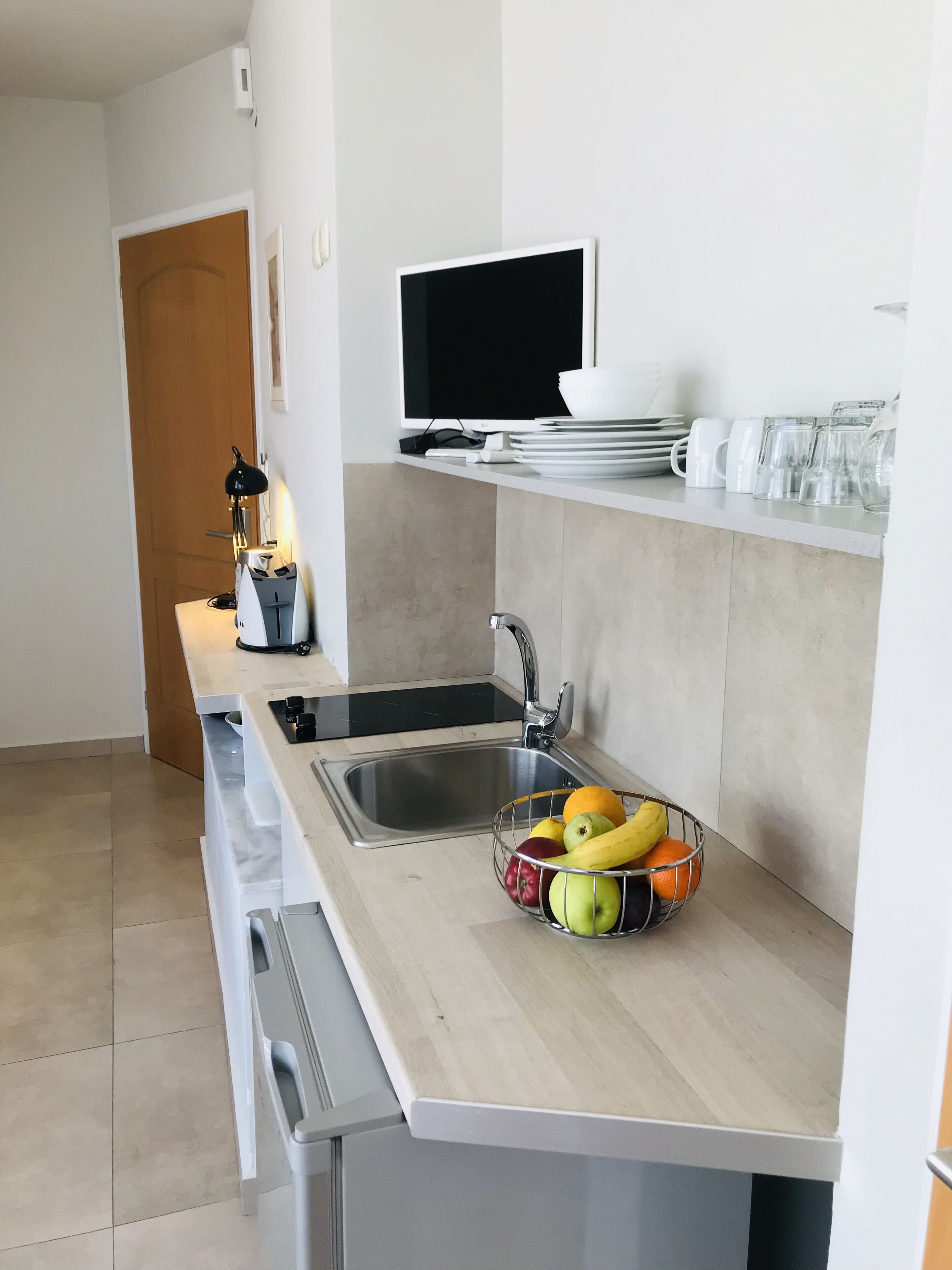 A modern kitchen with a sink, a countertop, and a fruit bowl.