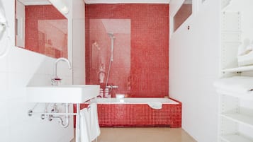 Ein modernes Badezimmer mit einer roten Duschwand, einem weißen Waschbecken und einer Badewanne.