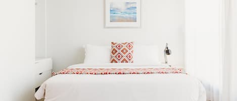 Une chambre d’hôtel avec un lit, une table de chevet, une lampe et un tableau encadré au mur.