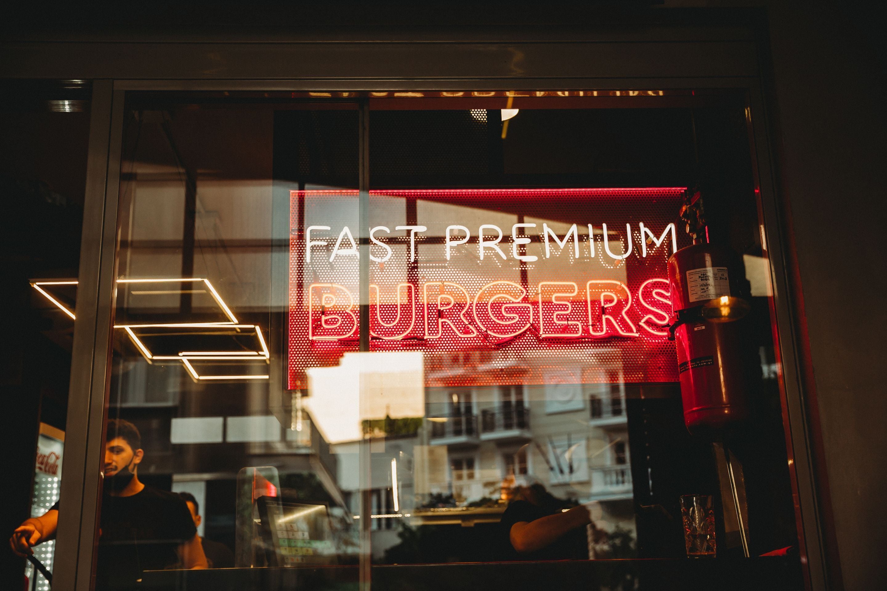 A restaurant window with a neon sign reading "FAST PREMIUM BURGERS".