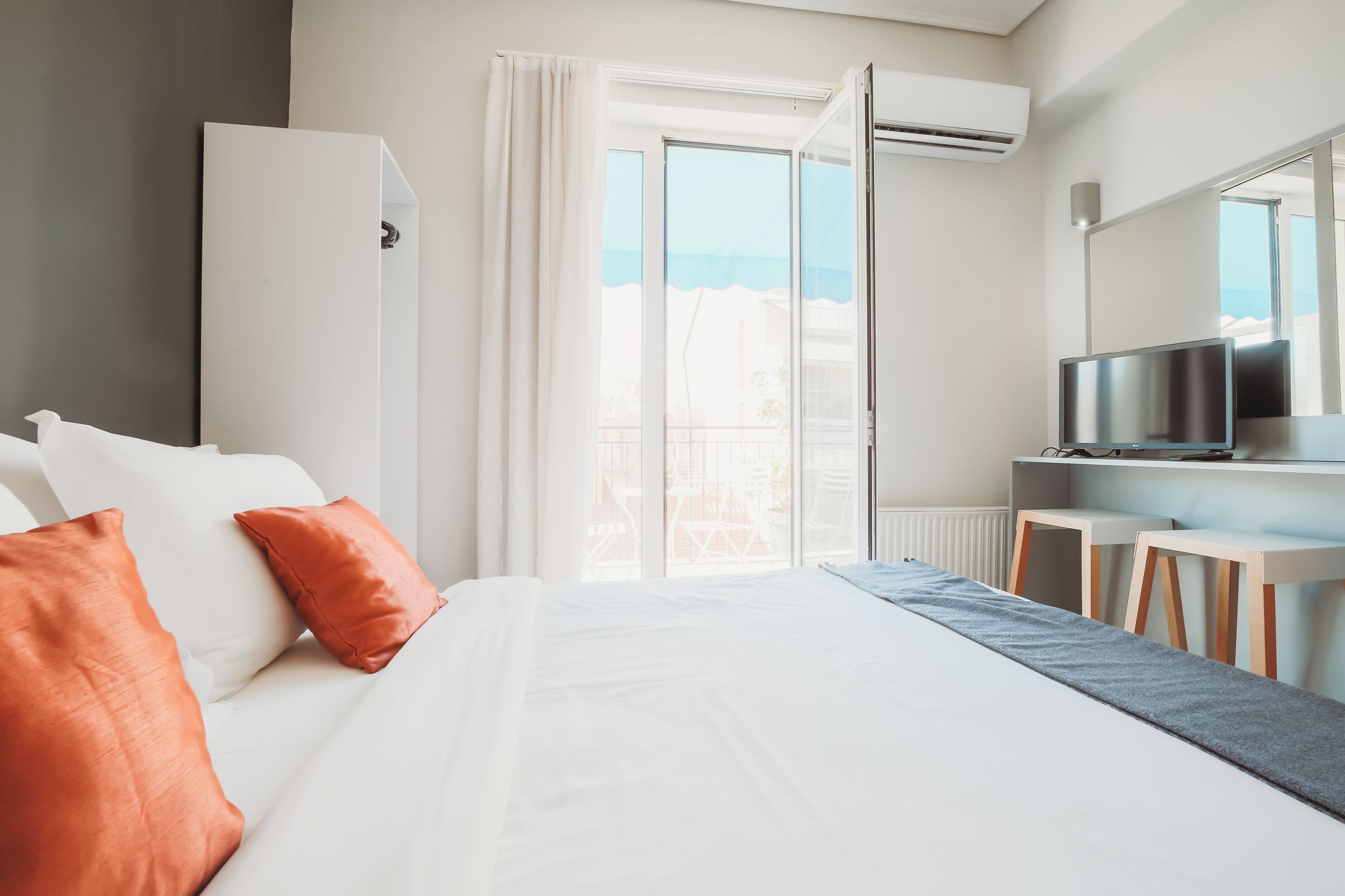Quarto de hotel com cama, televisão, escrivaninha e janela com vista para o mar.