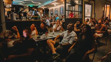En bardisk med sittande gäster vid borden, en bartender som blandar drinkar och en disk med olika typer av barutrustning.