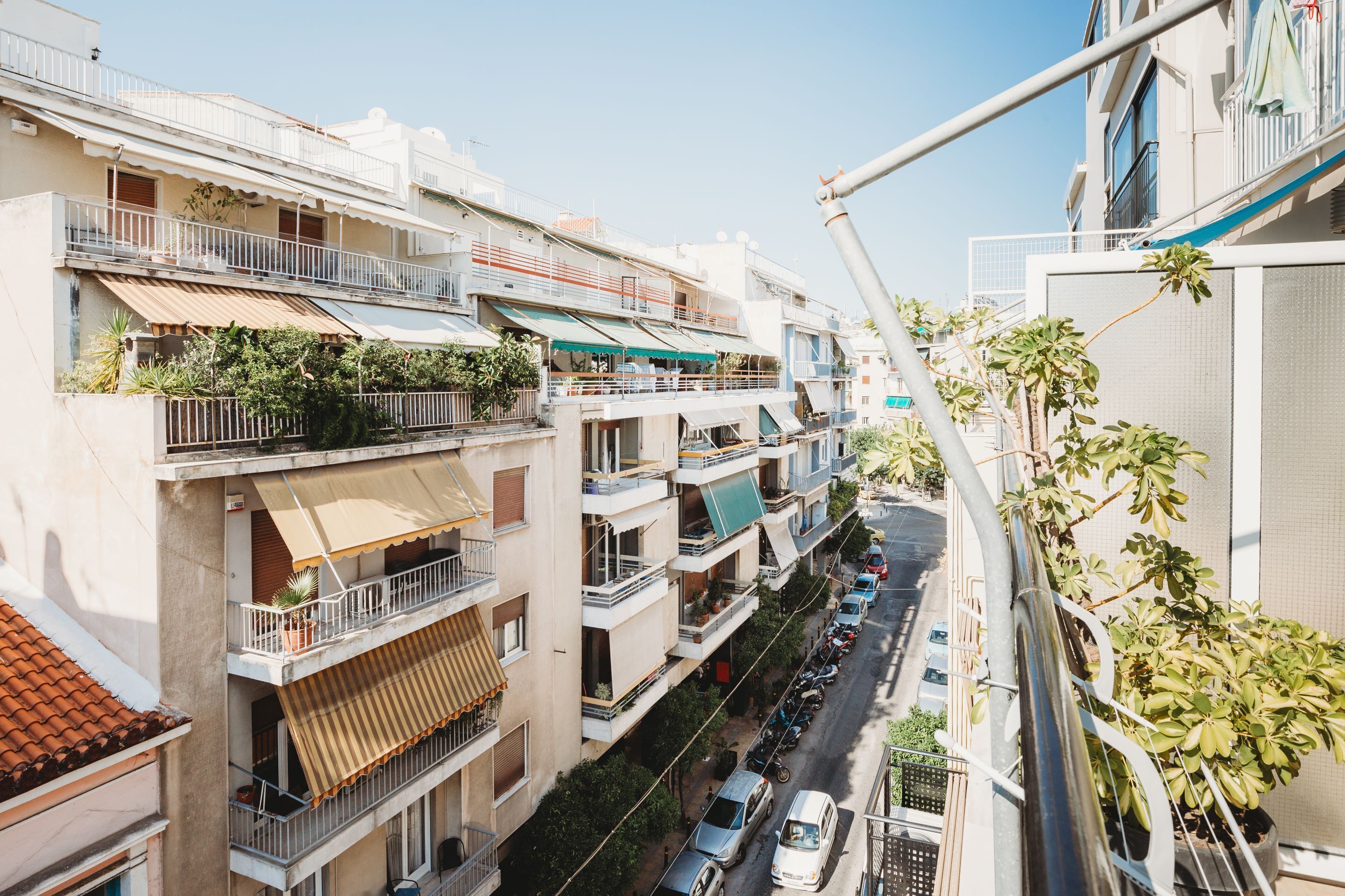 Un edificio residencial de varios pisos con balcones, una calle en primer plano y una grúa.