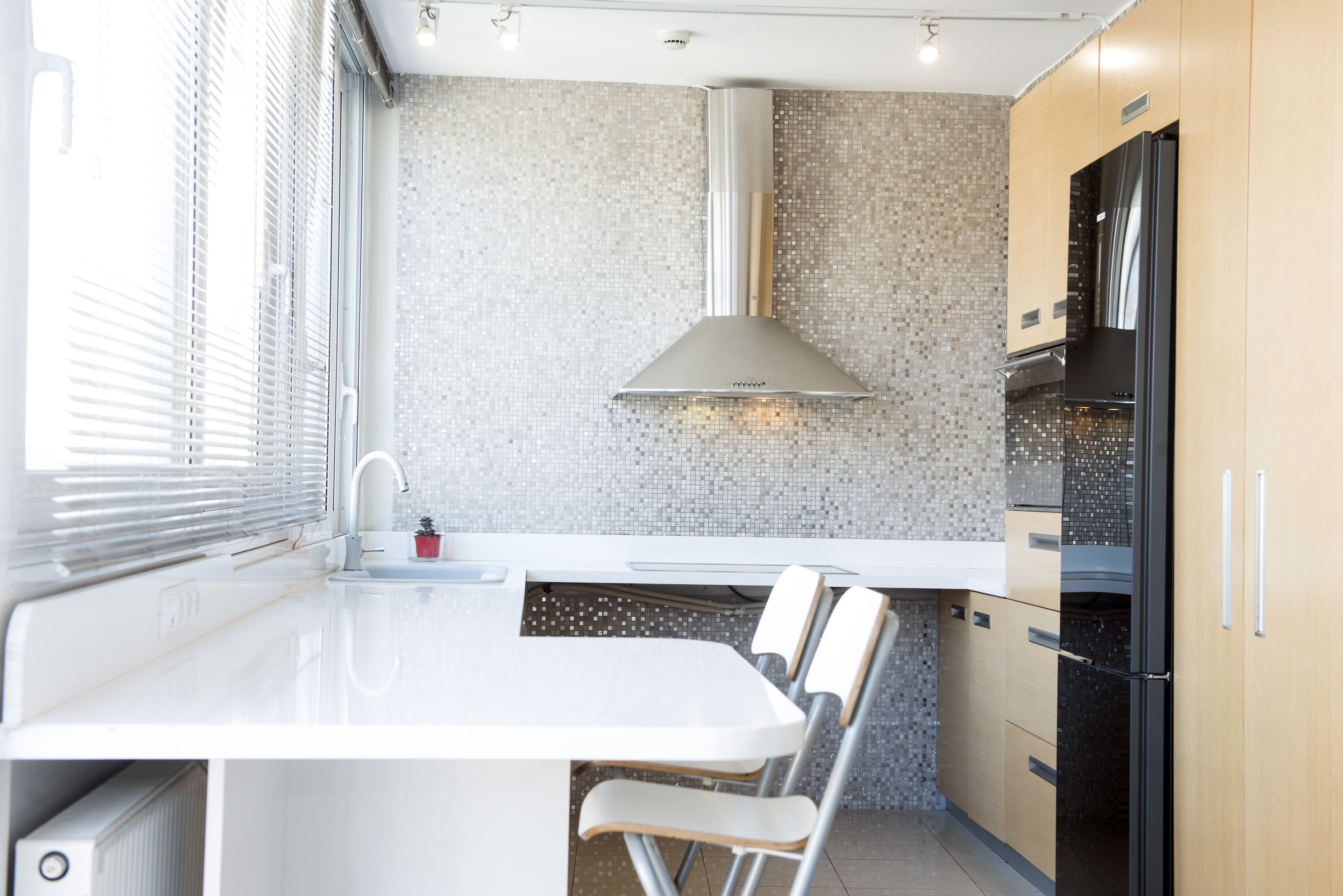 A modern kitchen with a white countertop, a built-in stove, and a black refrigerator.