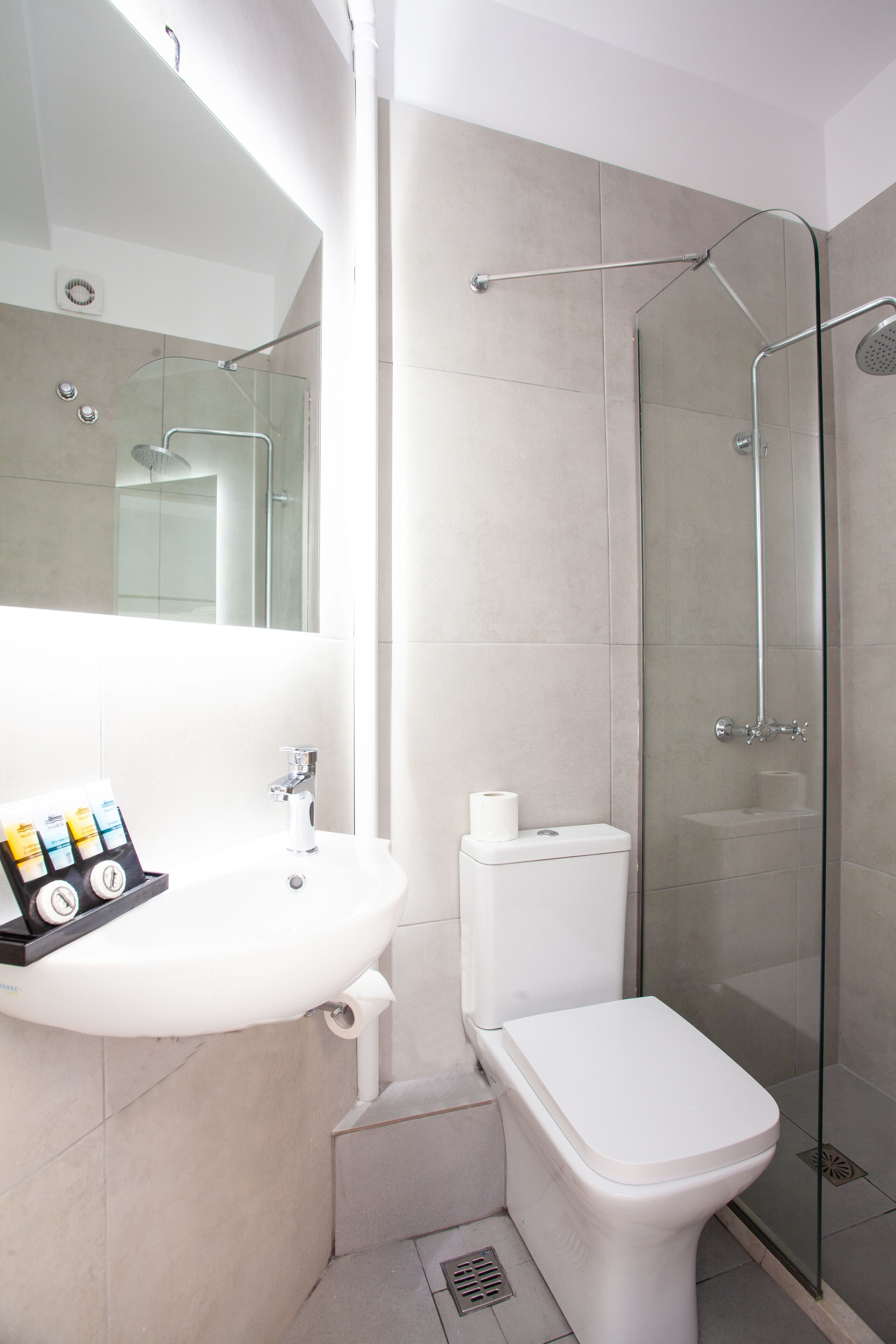 A modern bathroom with a glass-enclosed shower, a white sink, and a toilet.