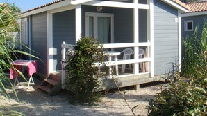 A small, single-story house with a porch, a table, and chairs.