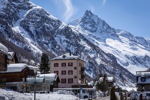Una località montana innevata con un hotel in evidenza, un autobus e lo sfondo di una montagna.