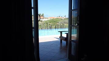 An open door leading to a pool area with a view of cacti and a distant landscape.