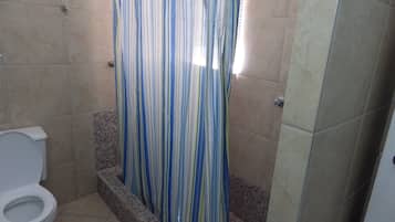 A bathroom with a shower curtain, a toilet, and tiled walls.