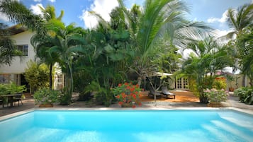 Piscina rodeada por vegetação tropical exuberante e um edifício com grandes janelas.