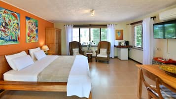Ein Hotelzimmer mit einem großen Bett, zwei Sessel, einem kleinen Tisch und einem Schreibtisch mit Kaffeemaschine.