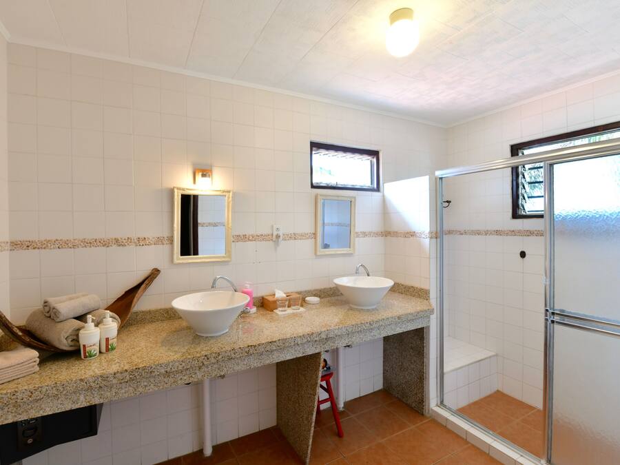 Un baño con dos lavamanos, ducha y tocador con perchero.