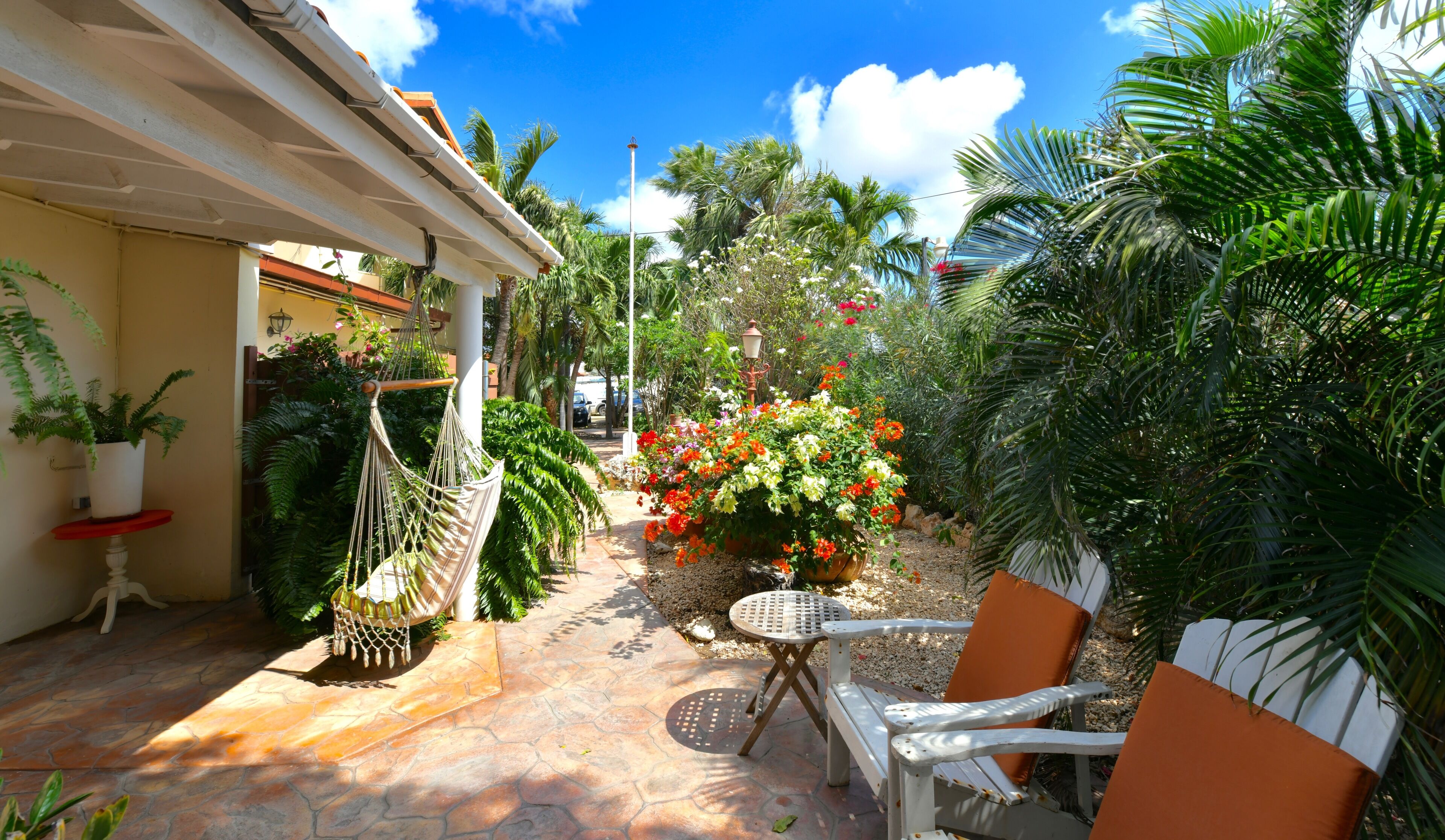 A patio area with a hammock, outdoor seating, and a variety of plants.