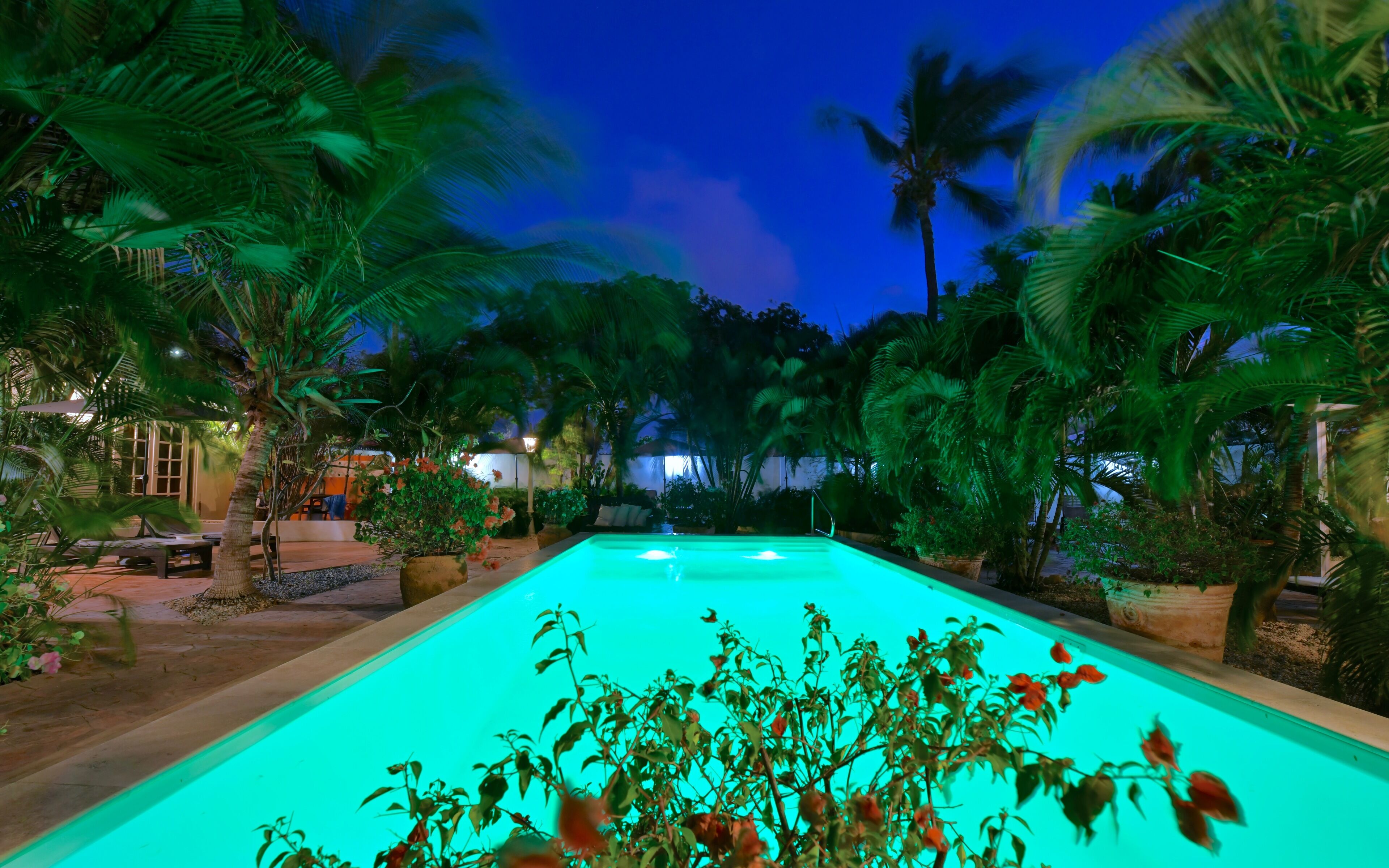 Una piscina al aire libre, sombrillas, sillones reclinables de piscina