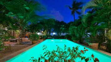Una piscina al aire libre, sombrillas, sillones reclinables de piscina