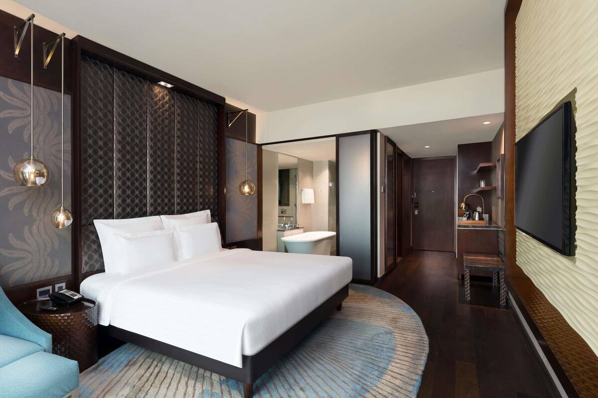 Une chambre dâhĂŽtel moderne dotĂ©e dâun grand lit, dâun coin salon, dâune salle de bain et dâune tĂ©lĂ©vision.