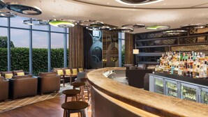 Un espace bar moderne doté d’un comptoir incurvé, de sièges et d’une variété de bouteilles.