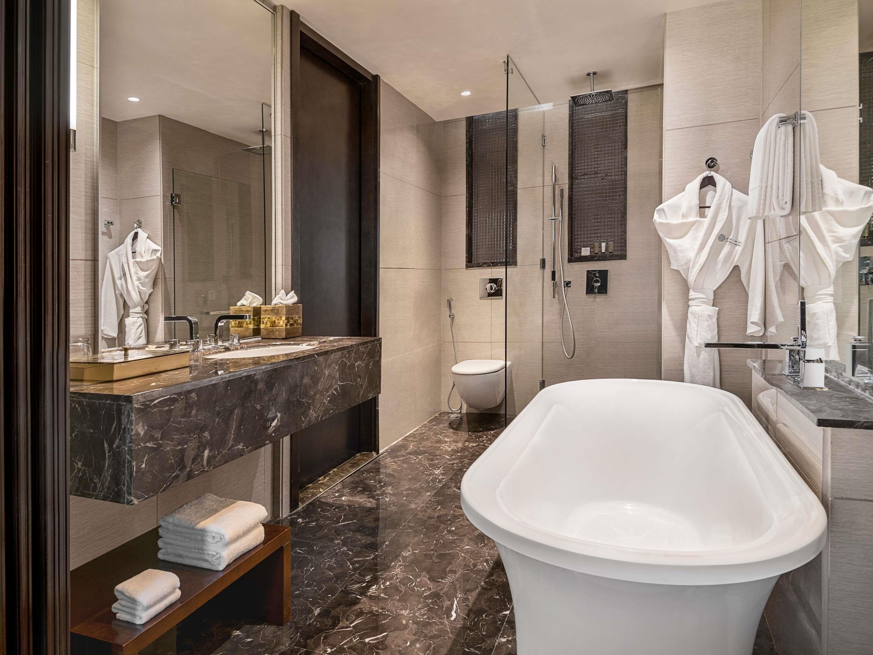 A modern bathroom with a large freestanding bathtub, a glass-enclosed shower, and a marble vanity.