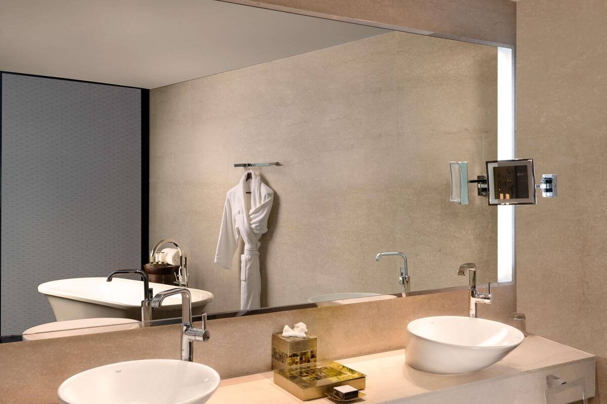 Een moderne badkamer met twee wasbakken, een grote spiegel en een handdoekrek.