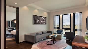Una sala de estar moderna con un sofá, una mesita de centro y una zona de comedor con una mesa y sillas. Hay un ventanal con vistas al exterior.