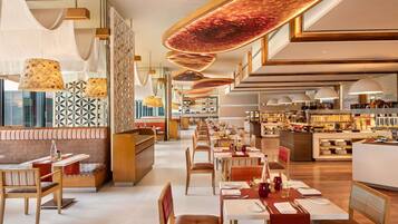 A modern restaurant with high ceilings, pendant lighting, and a central bar area.