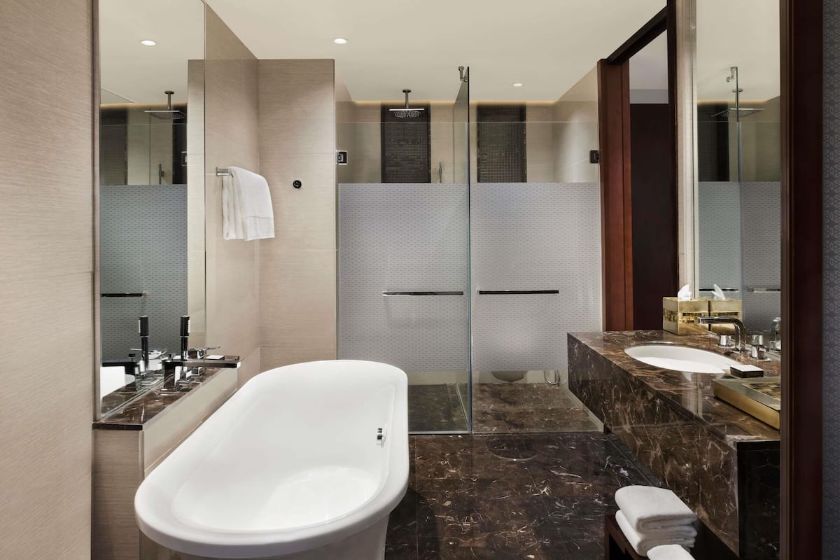 Ein modernes Badezimmer mit freistehender Badewanne, einer Duschkabine und einem Waschtisch mit Marmorplatte.
