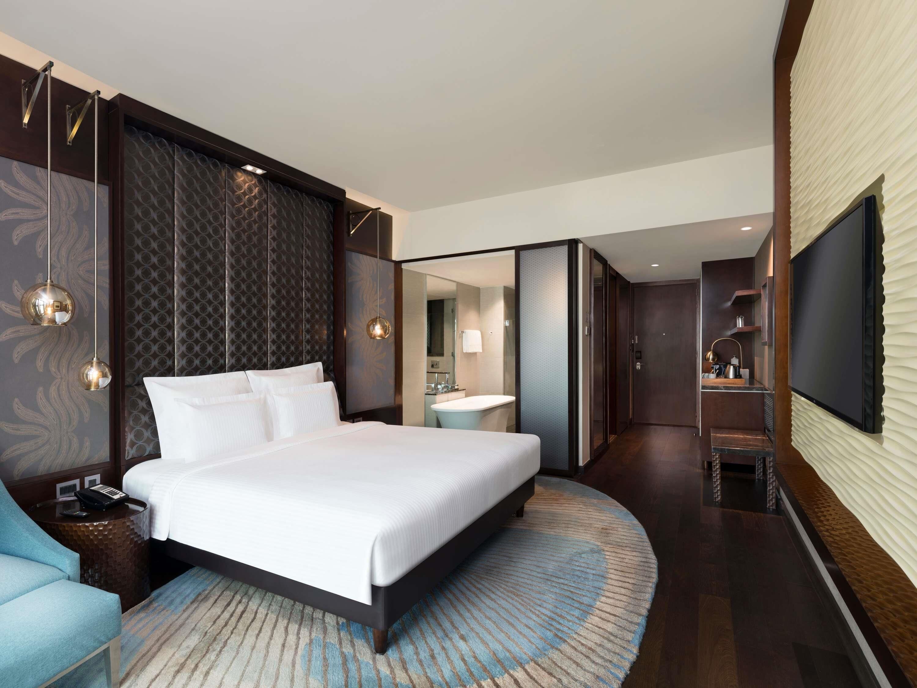 Une chambre d’hôtel moderne dotée d’un grand lit, d’une salle de bain, d’une télévision et d’un coin salon.