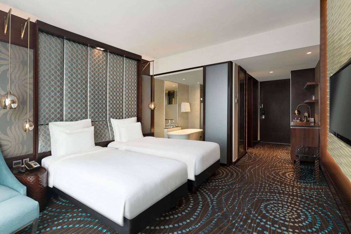 Een hotelkamer met twee bedden, een zithoek, een badkamer en een televisie.