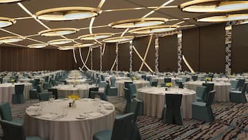 Un gran salón de banquetes con mesas redondas, sillas color turquesa y una alfombra estampada.