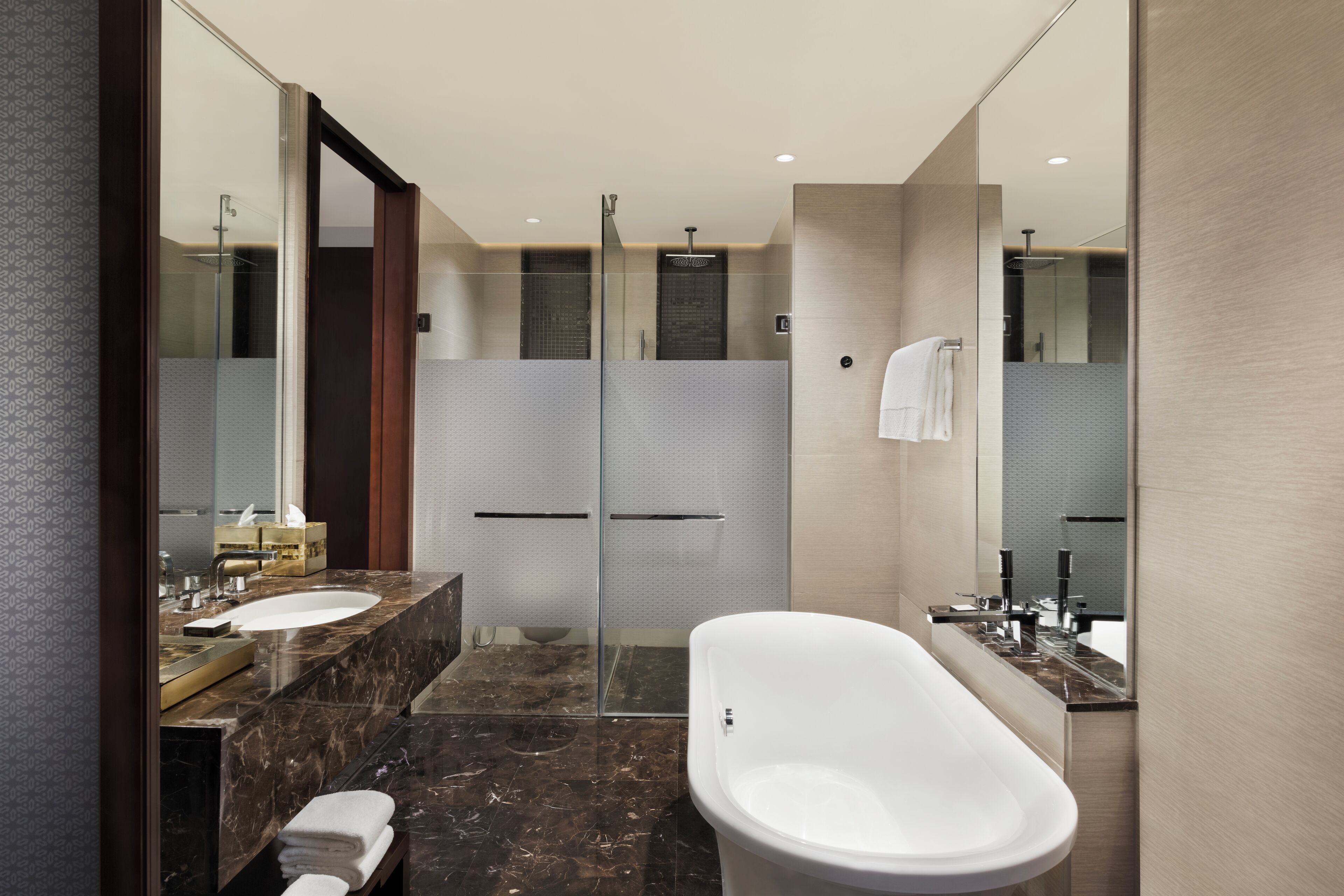 A modern bathroom with a glass shower enclosure, a freestanding bathtub, and a vanity with a sink and mirror.