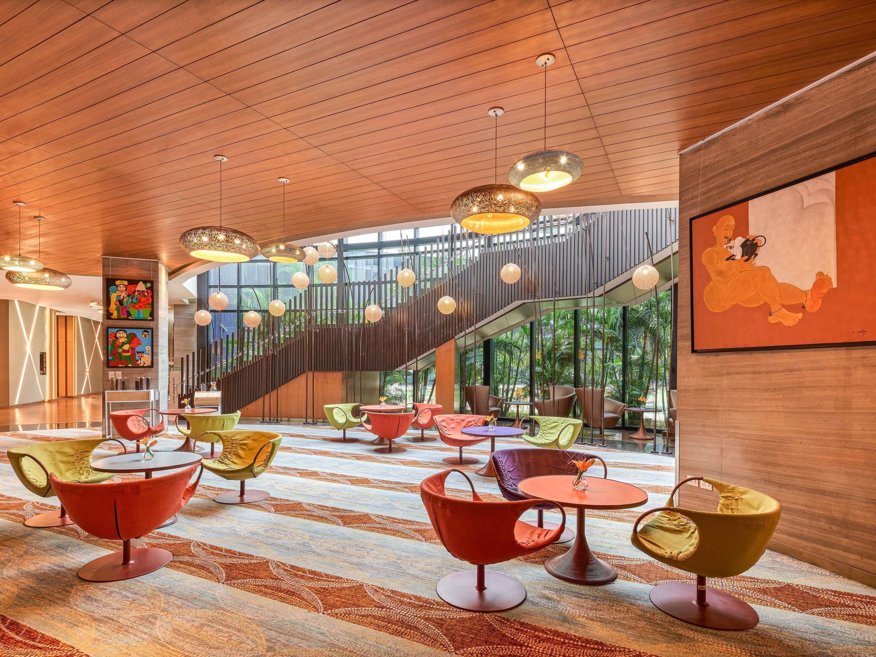 A modern interior with a wooden ceiling, colorful chairs, and a staircase.
