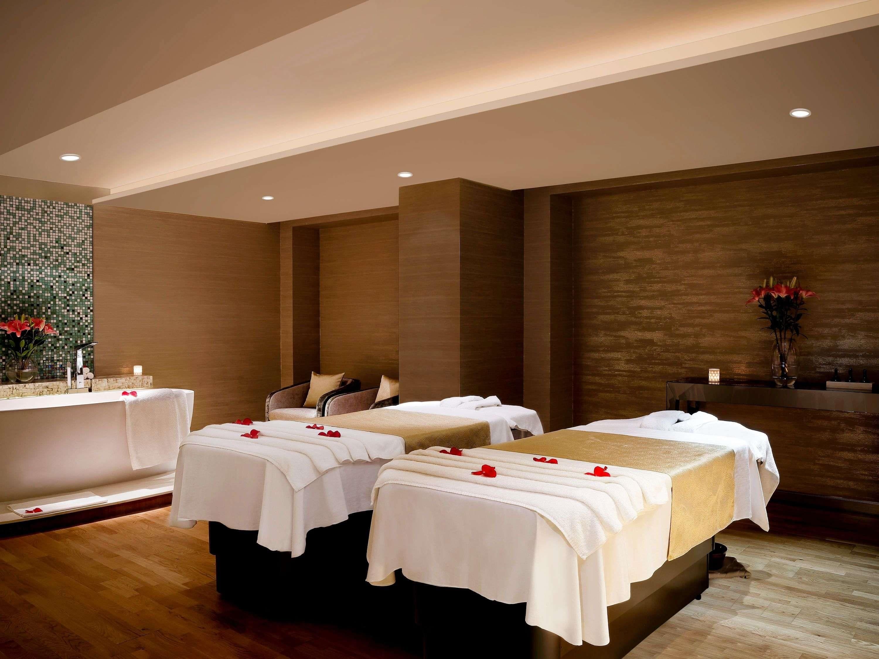 Ein Spa-Raum mit zwei Massagetischen, einer Badewanne und einer Wand mit einem Mosaikmuster.