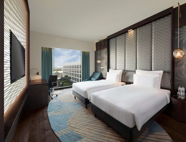 A hotel room with two beds, a desk, a chair, and a large window with a city view. - Pullman New Delhi Aerocity Hotel (New Delhi)