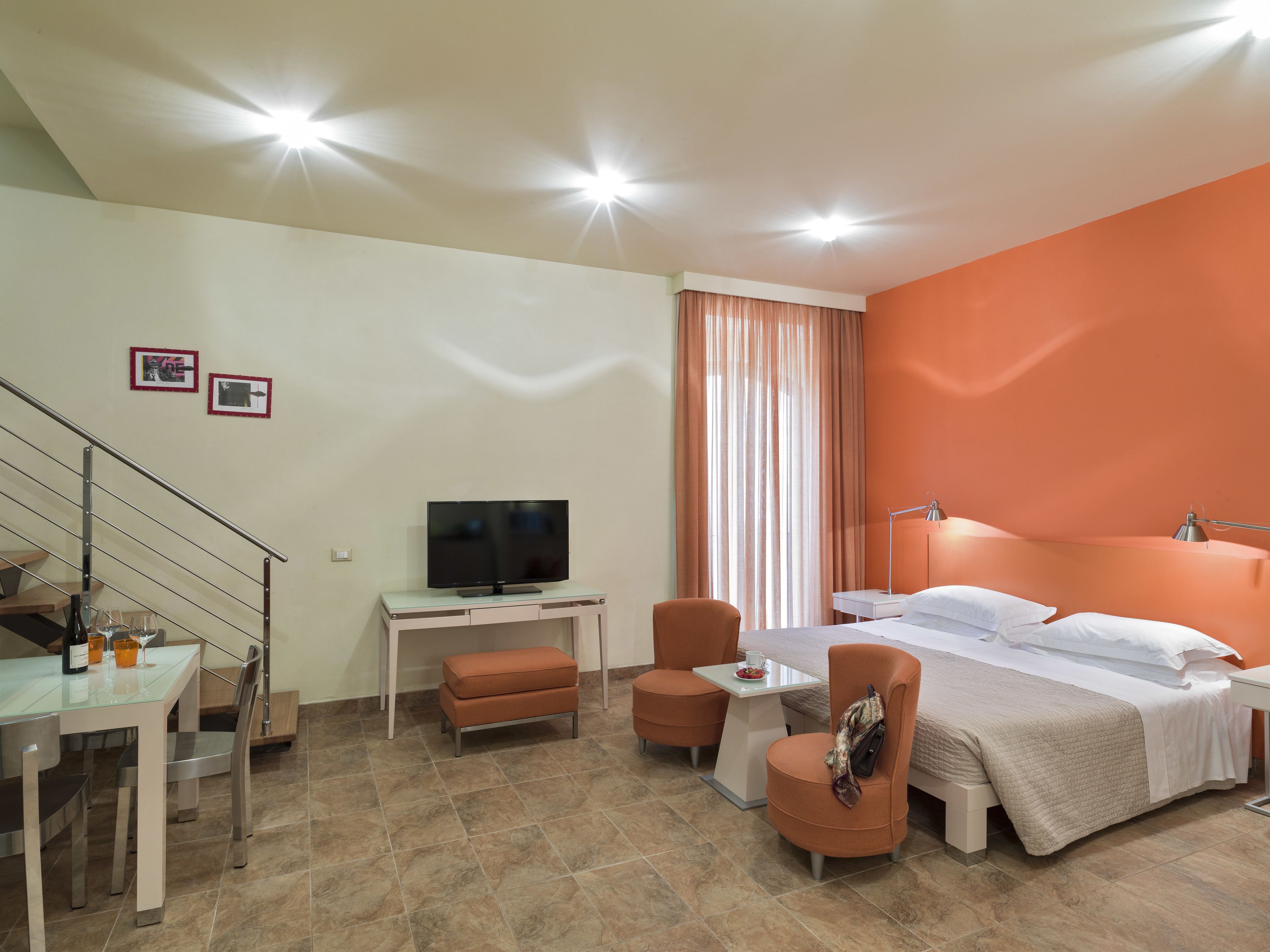 Een hotelkamer met een bed, een bureau met een televisie, een stoel, een kleine tafel en een trap.