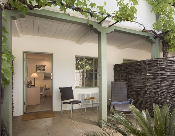 A covered patio area with a chair, a small table, and a wicker chair. - Indian Springs Resort & Spa (Calistoga)