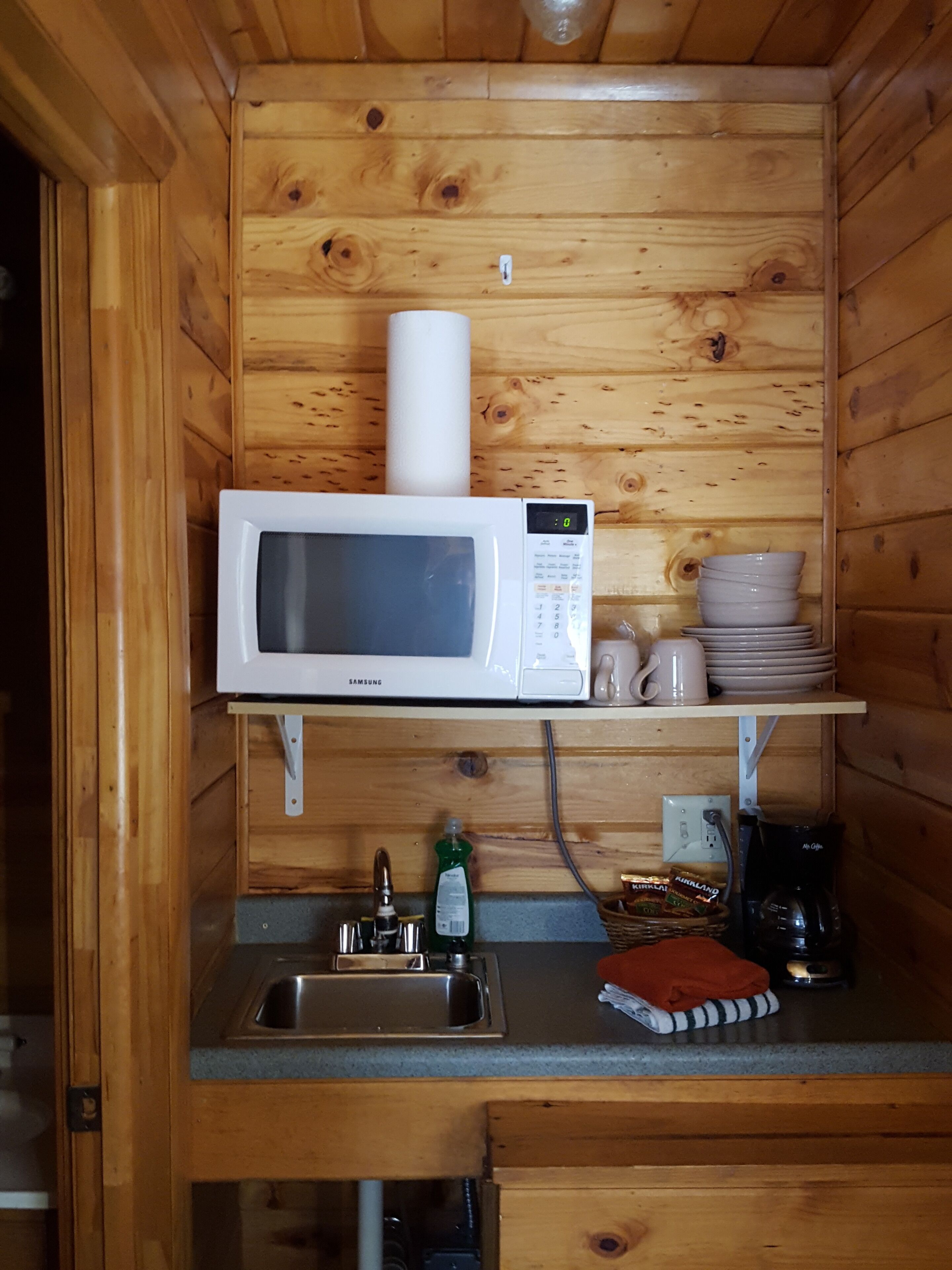 A compact kitchen with a white microwave, a sink, and a small countertop.