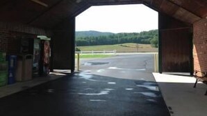 An open-air structure with a brick interior and a view of a green landscape. - Village Inn (Lovingston)