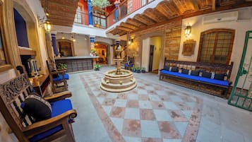 A courtyard with a fountain, seating areas, and a staircase leading to an upper level.
