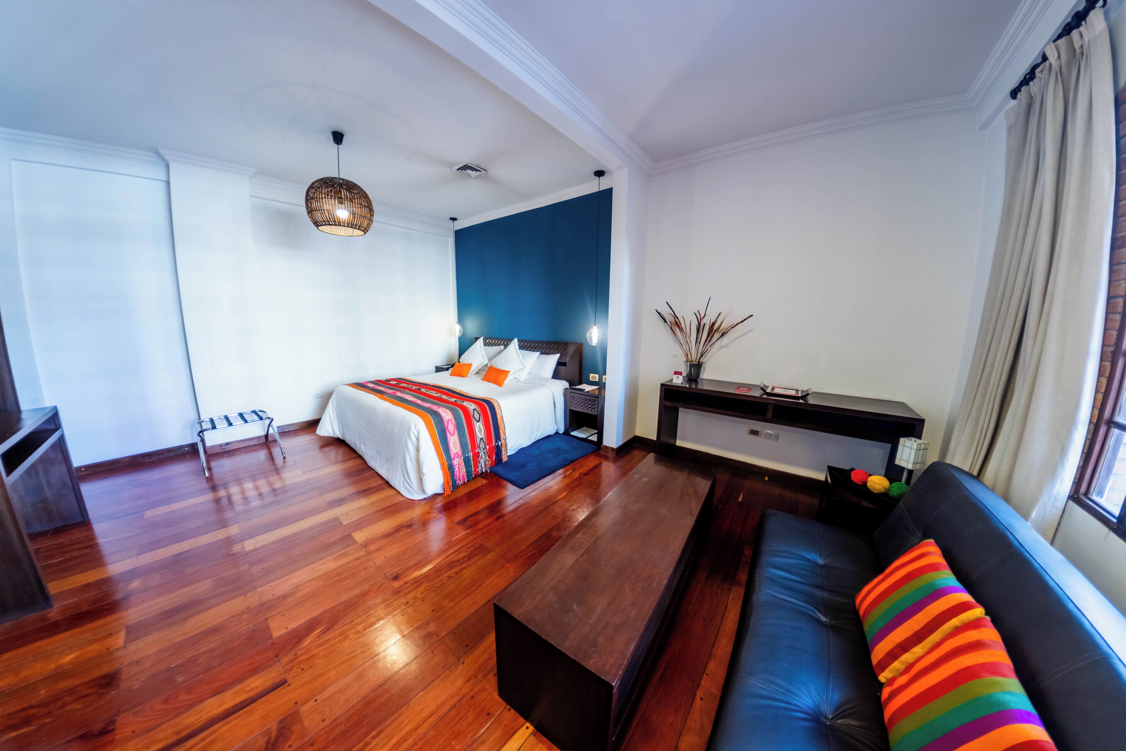 Una habitación de hotel moderna con una cama, un sofá, una mesita de centro, un escritorio y una ventana.