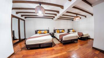 A hotel room with two beds, wooden flooring, and a sloped ceiling with exposed beams.