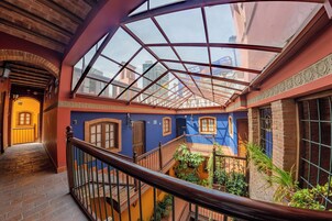 Ein überdachter Innenhof mit Glasdach, einer Treppe und Blick auf die umliegenden Gebäude.