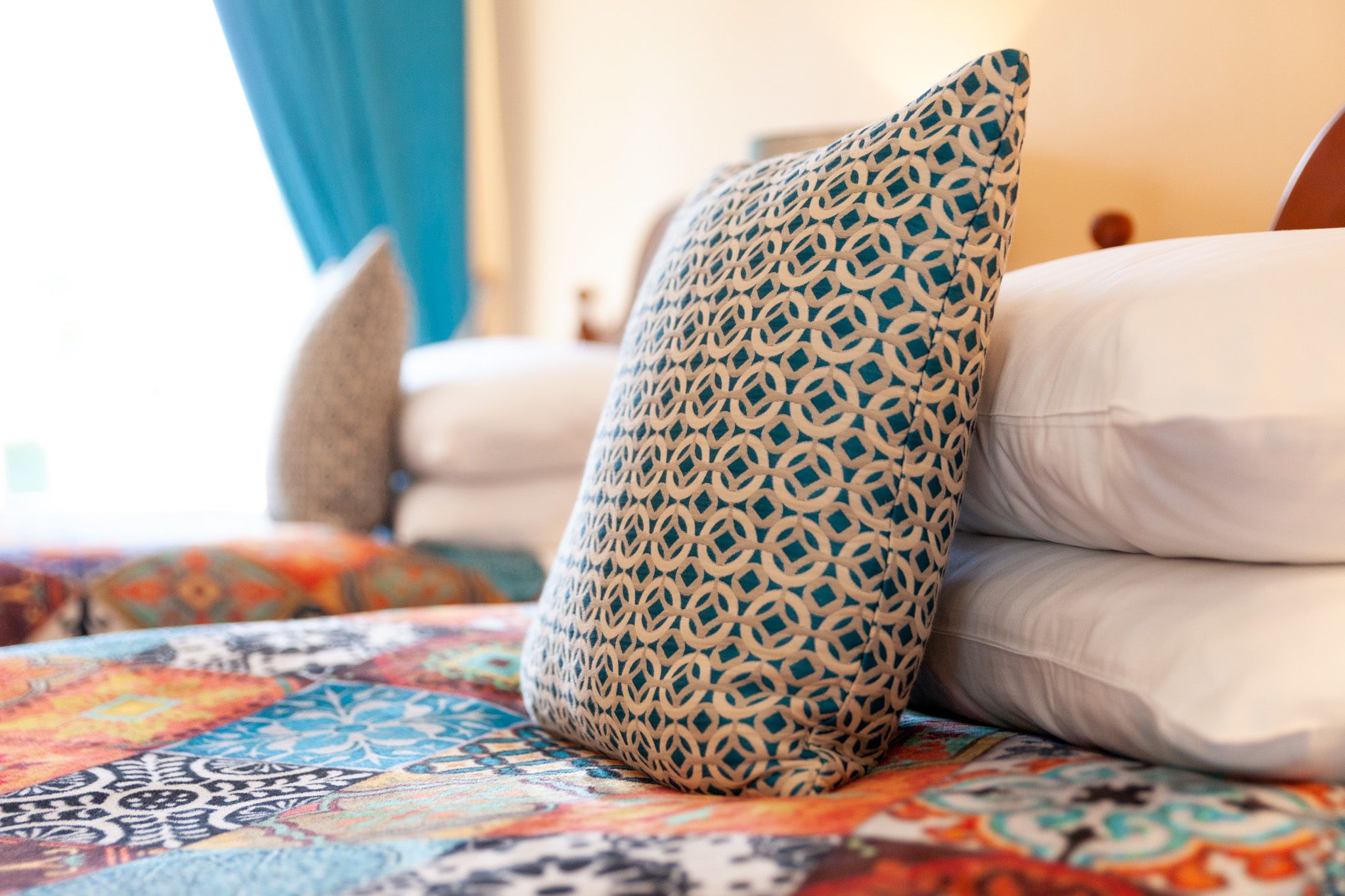 A bed with patterned pillows and a colorful quilt.