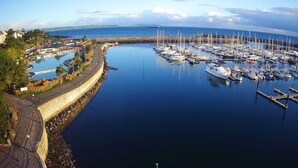 A marina with numerous boats docked, a curved pathway along the water, and a distant view of the coastline. - Shelleven House (Bangor)