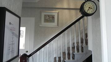 Un escalier avec des balustrades blanches et une horloge au-dessus.