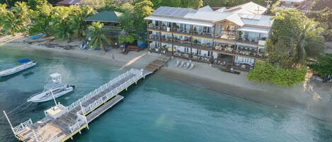 Un hotel frente al mar con muelle, barcos y una playa.