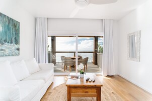 Un salón moderno con un sofá blanco, una mesa de centro de madera y vistas al balcón con zona de comedor.