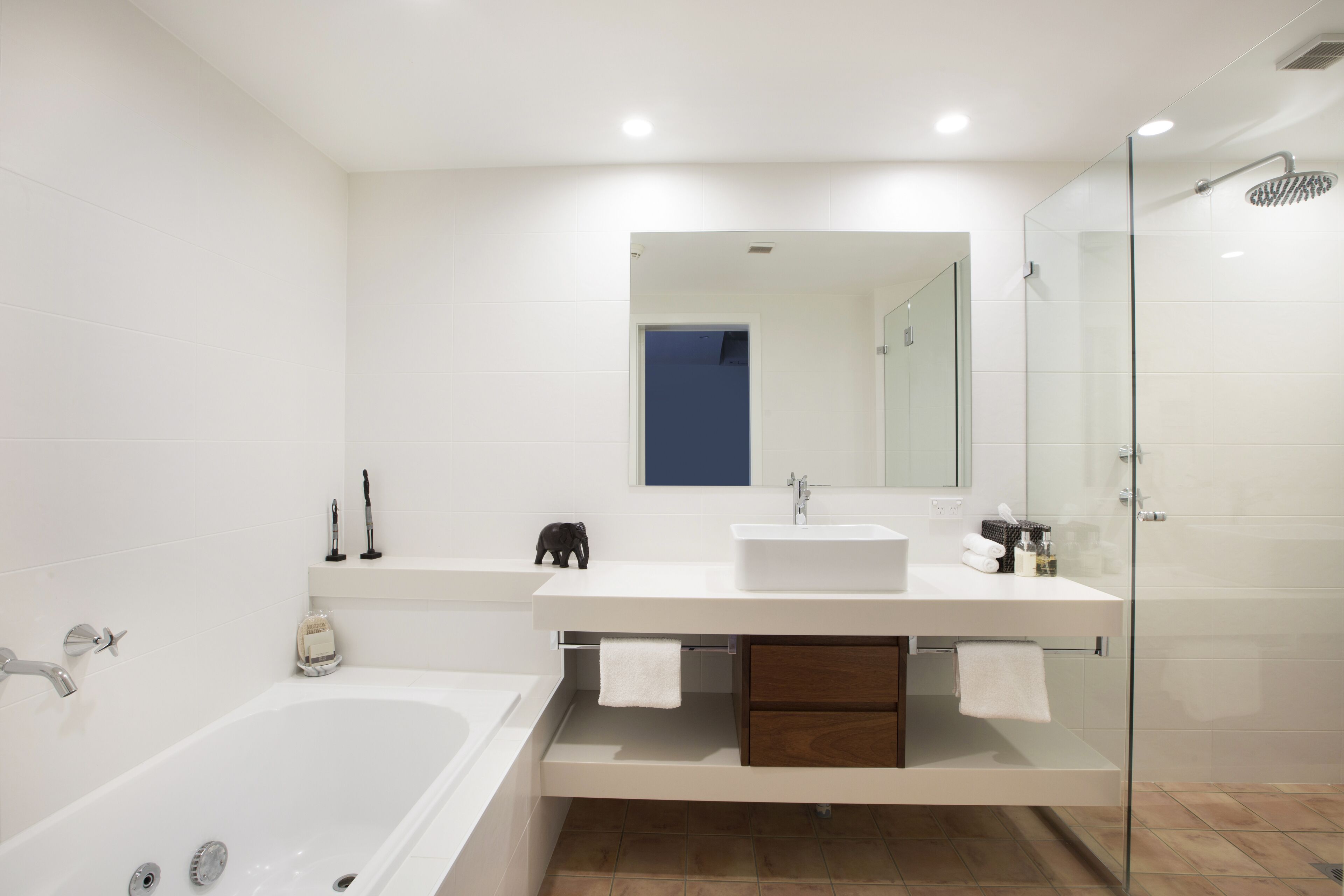 Un baño moderno con bañera, un espejo grande, cabina de ducha de vidrio y tocador blanco con lavabo.