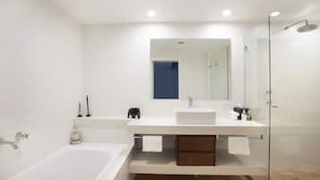 Un baño moderno con bañera, un espejo grande, cabina de ducha de vidrio y tocador blanco con lavabo.